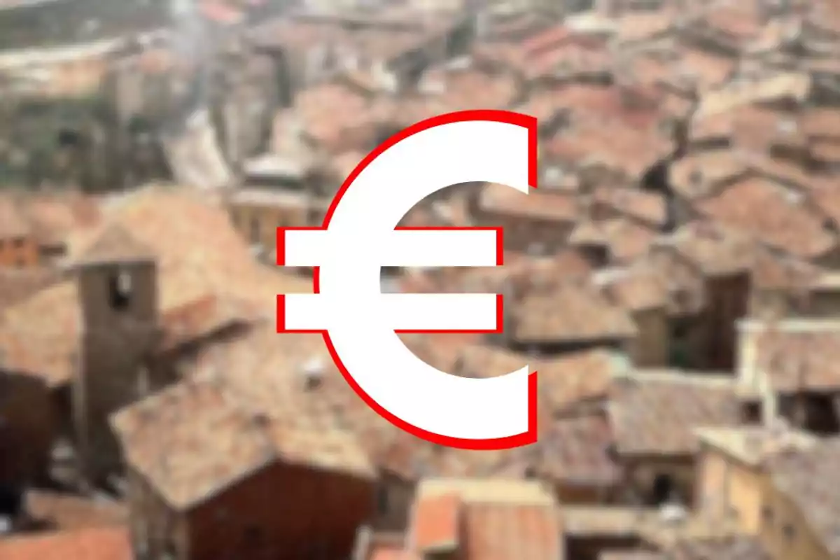 Símbol de l’euro en gran sobre un fons borros de teulades de cases antigues