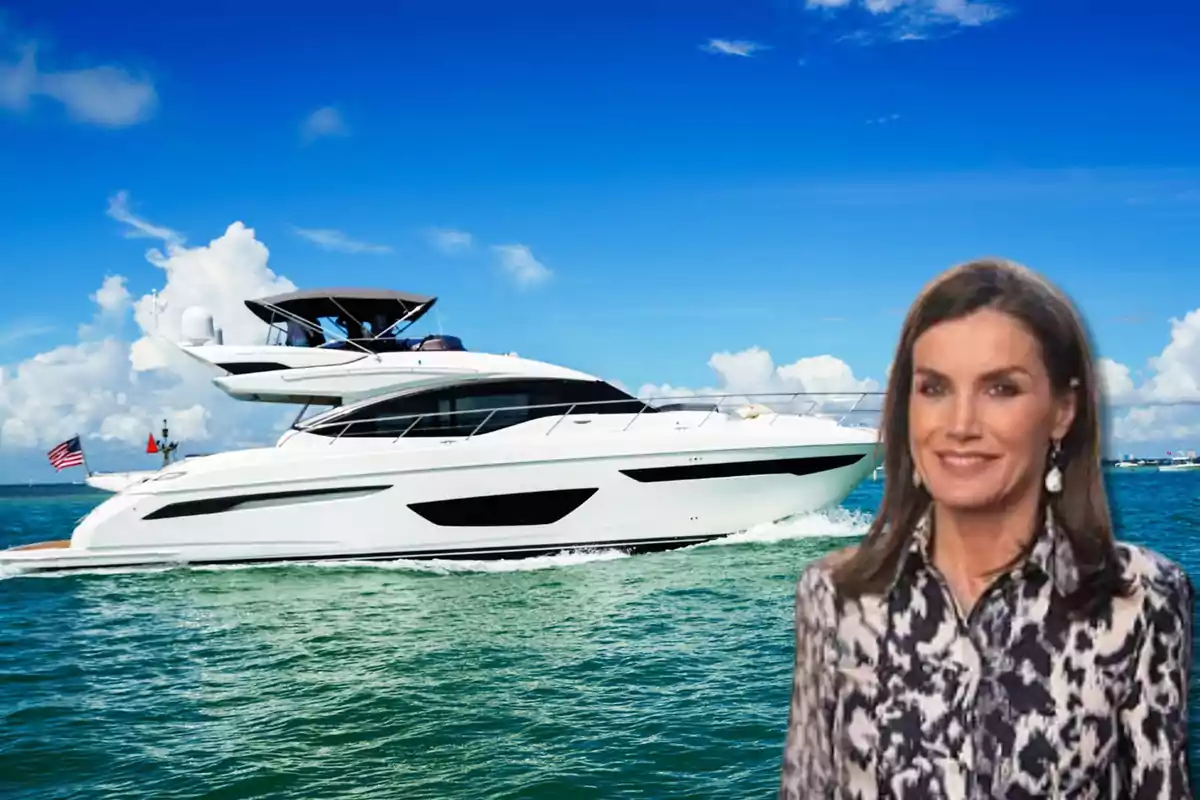 Una mujer sonriente con cabello castaño y blusa estampada frente a un yate blanco en el mar con cielo azul y nubes.