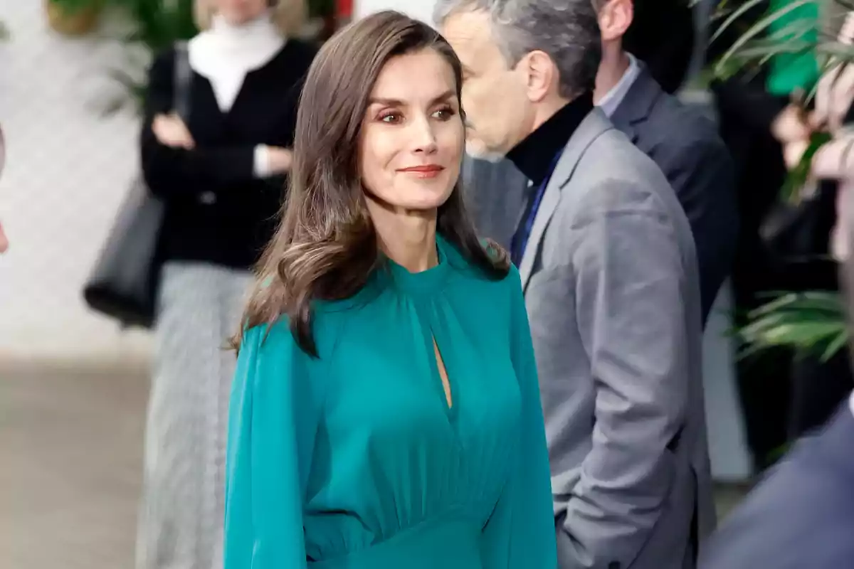 La imatge mostra la reina Letícia amb un vestit verd en un entorn social. La imatge mostra la reina Letícia amb un vestit verd en un entorn social.