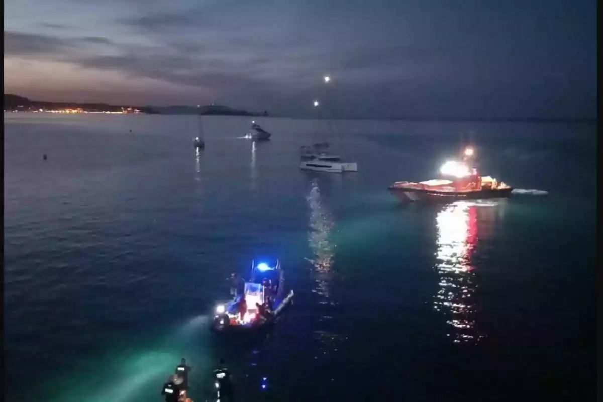 Diverses embarcacions amb els llums encesos duen a terme un operatiu nocturn al mar a prop de la costa.