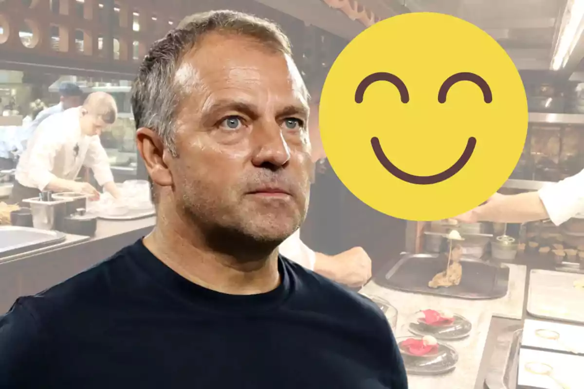 Un home amb expressió seriosa està en primer pla, mentre que al fons es veu una cuina amb xefs treballant; un emoji somrient cobreix part de la imatge.