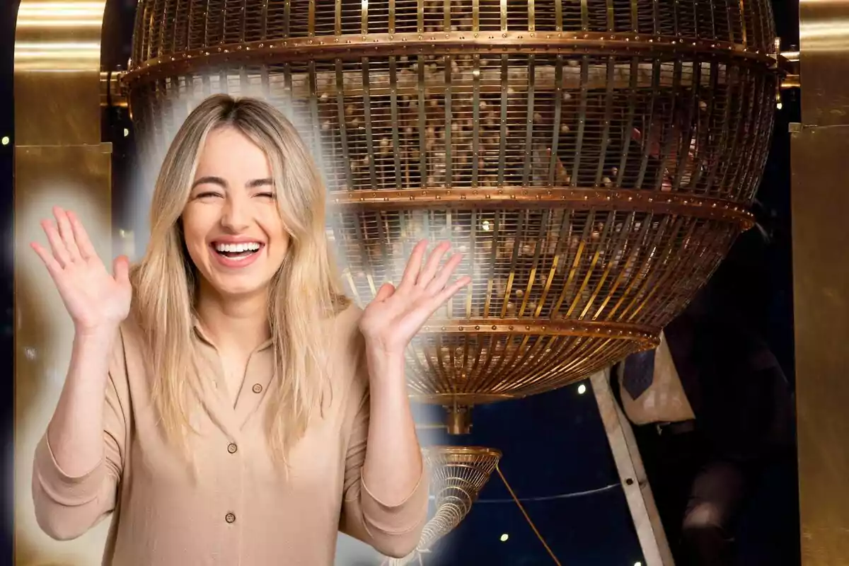 Una mujer sonriente con las manos levantadas frente a una gran esfera metálica.