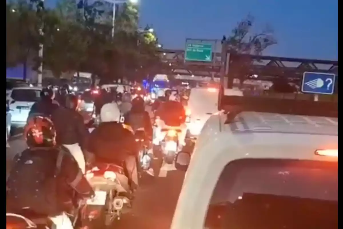 Trànsit dens en una carretera amb motocicletes i cotxes al capvespre.