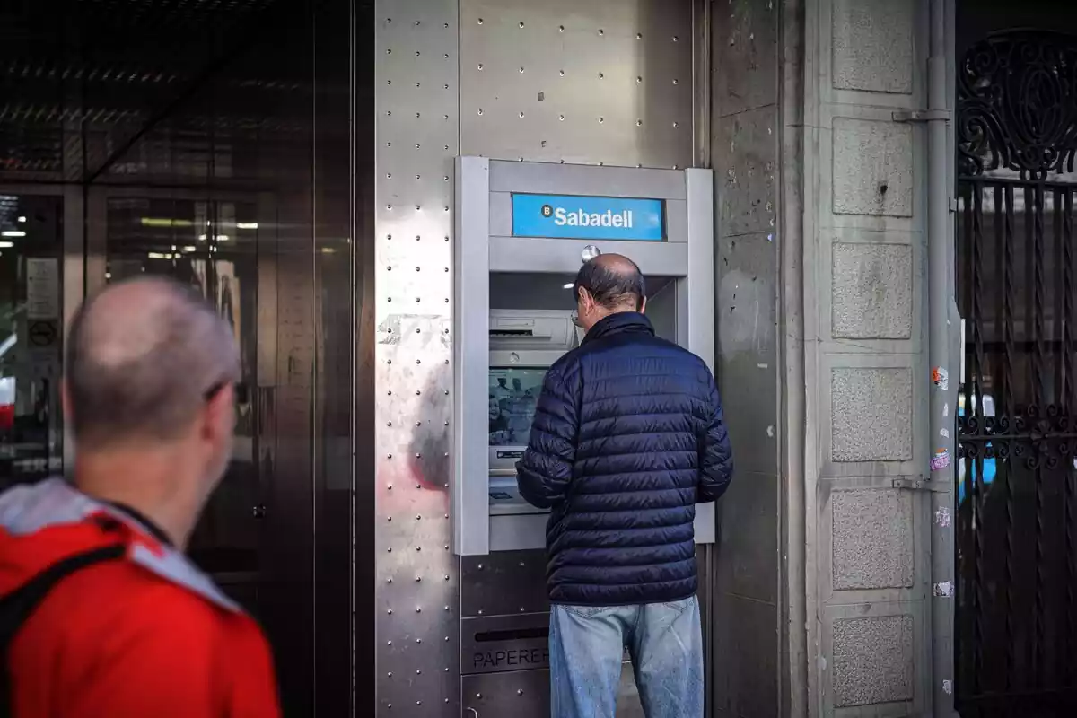 Un home dret traient diners d?un caixer del Banc Sabadell