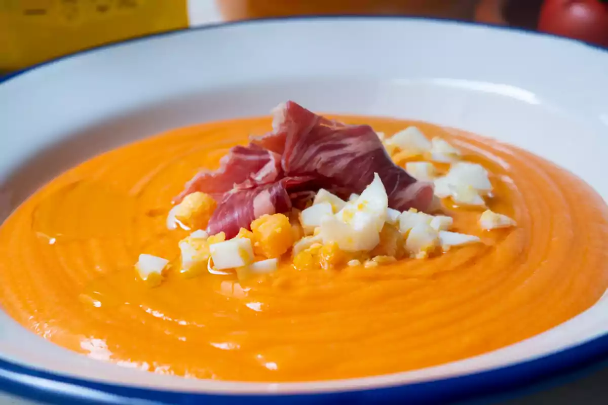 Un plat de salmorejo amb trossos d'ou dur i pernil salat.