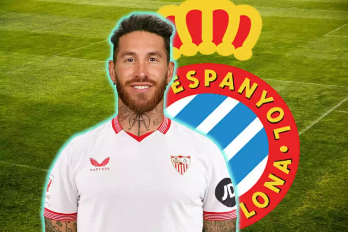 Un jugador de futbol amb la samarreta del Sevilla FC posant davant de l'escut del RCD Espanyol en un camp de futbol.