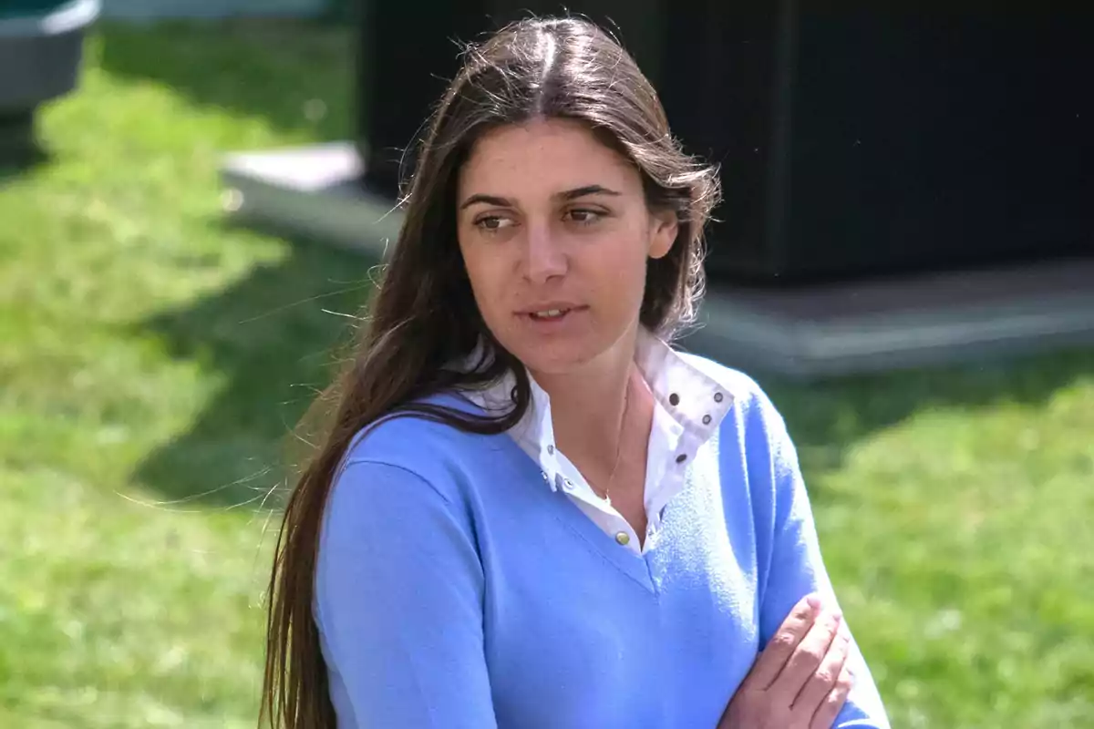Sira Martínez lleva un suéter azul claro sobre una camisa blanca mientras está al aire libre en un área con césped. Sira Martínez lleva un suéter azul claro sobre una camisa blanca mientras está al aire libre en un área con césped.