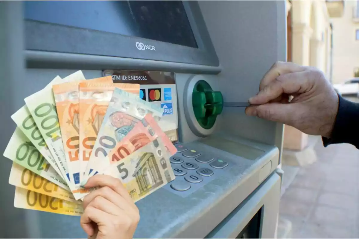 Persona insertando una tarjeta en un cajero automático mientras sostiene billetes de euro en la otra mano.