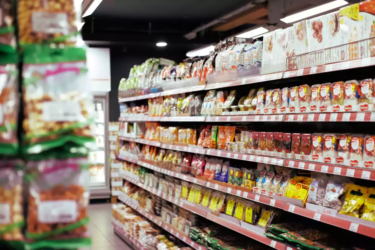 Pasillo de supermercado con estantes llenos de productos variados en bolsas y cajas