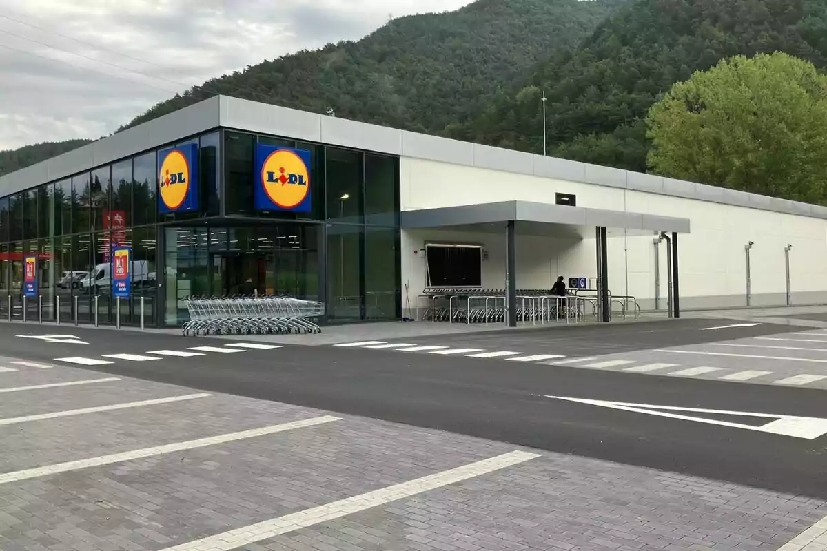 Façana d´un supermercat Lidl amb carros de compra al´entrada i un entorn muntanyós al fons.