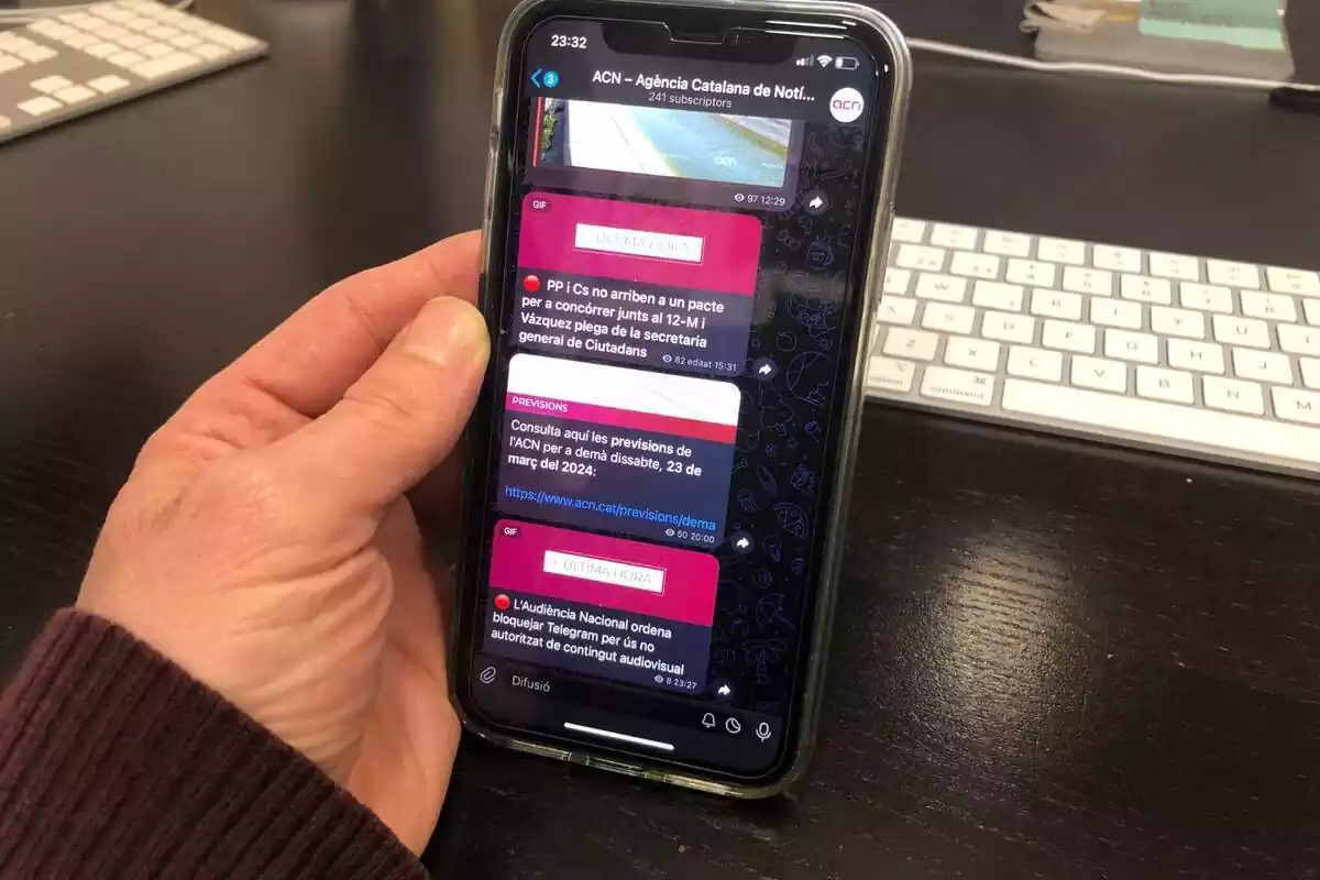 Una persona sostenint un smartphone on hi ha oberta l'aplicació Telegram