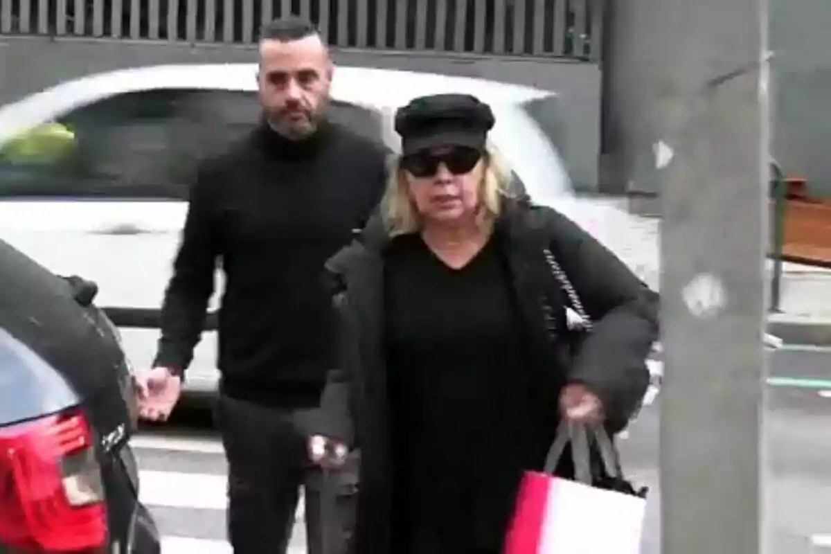 Dos personas caminando por la calle, una de ellas lleva gafas de sol y una bolsa.