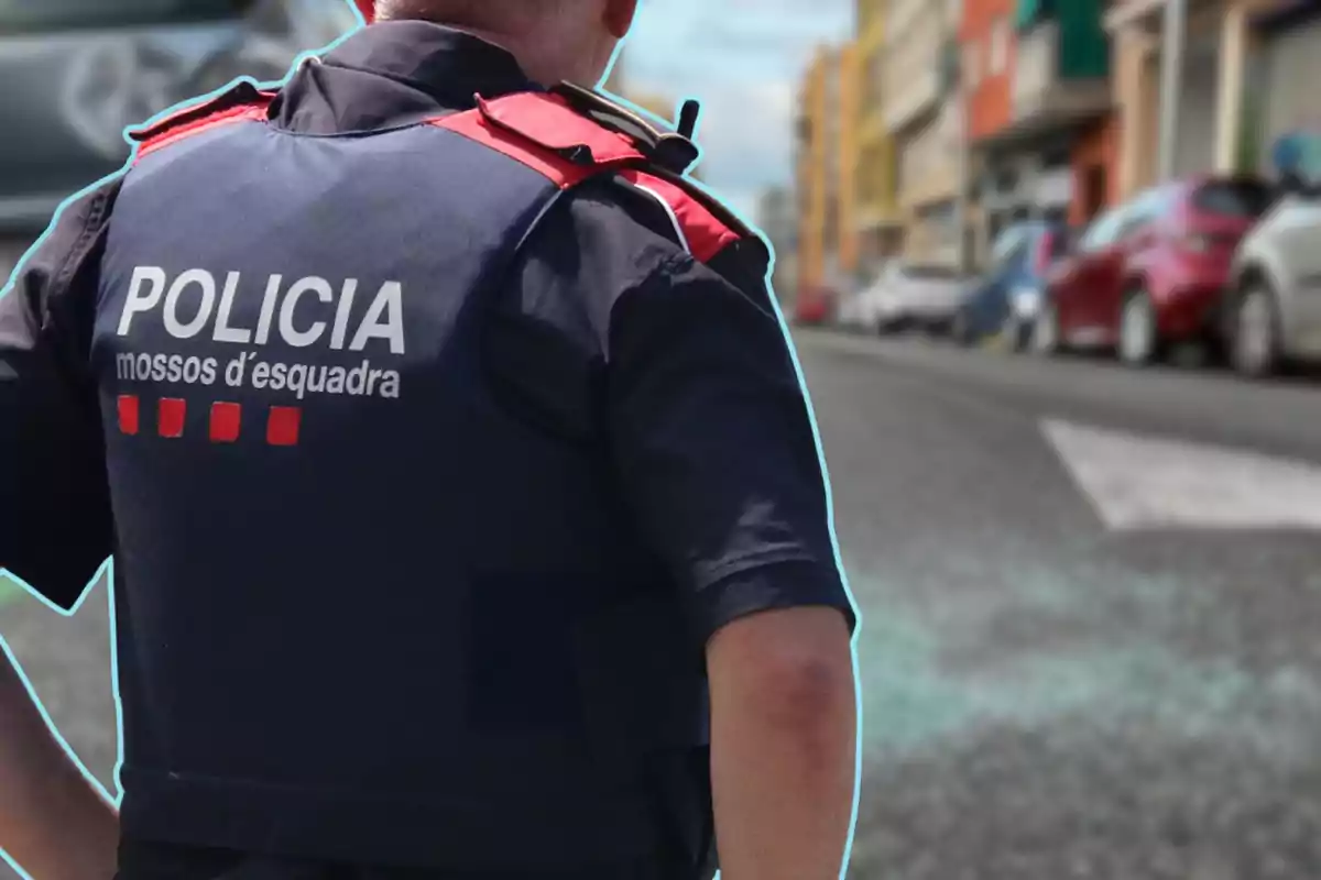 Un agent dels Mossos d'Esquadra d'esquena a un carrer amb cotxes estacionats.