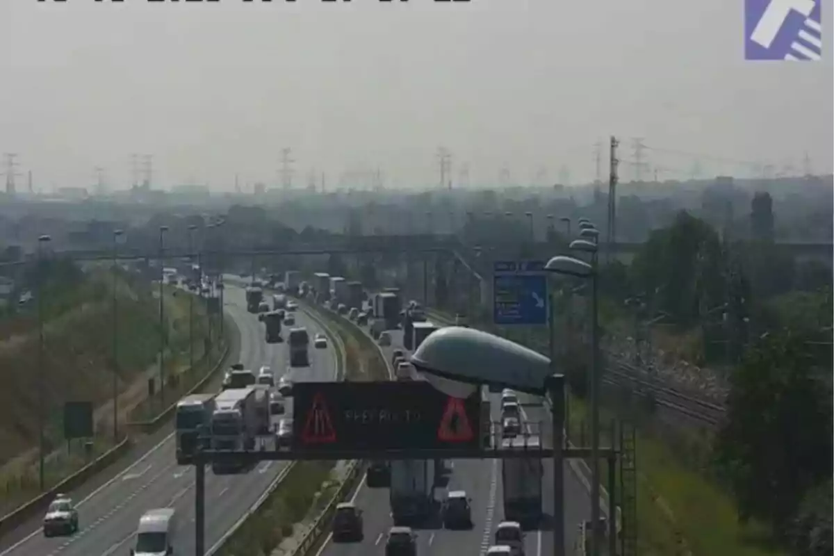 Trànsit dens en una autopista amb diversos carrils i vehicles circulant en ambdues direccions sota un cel ennuvolat