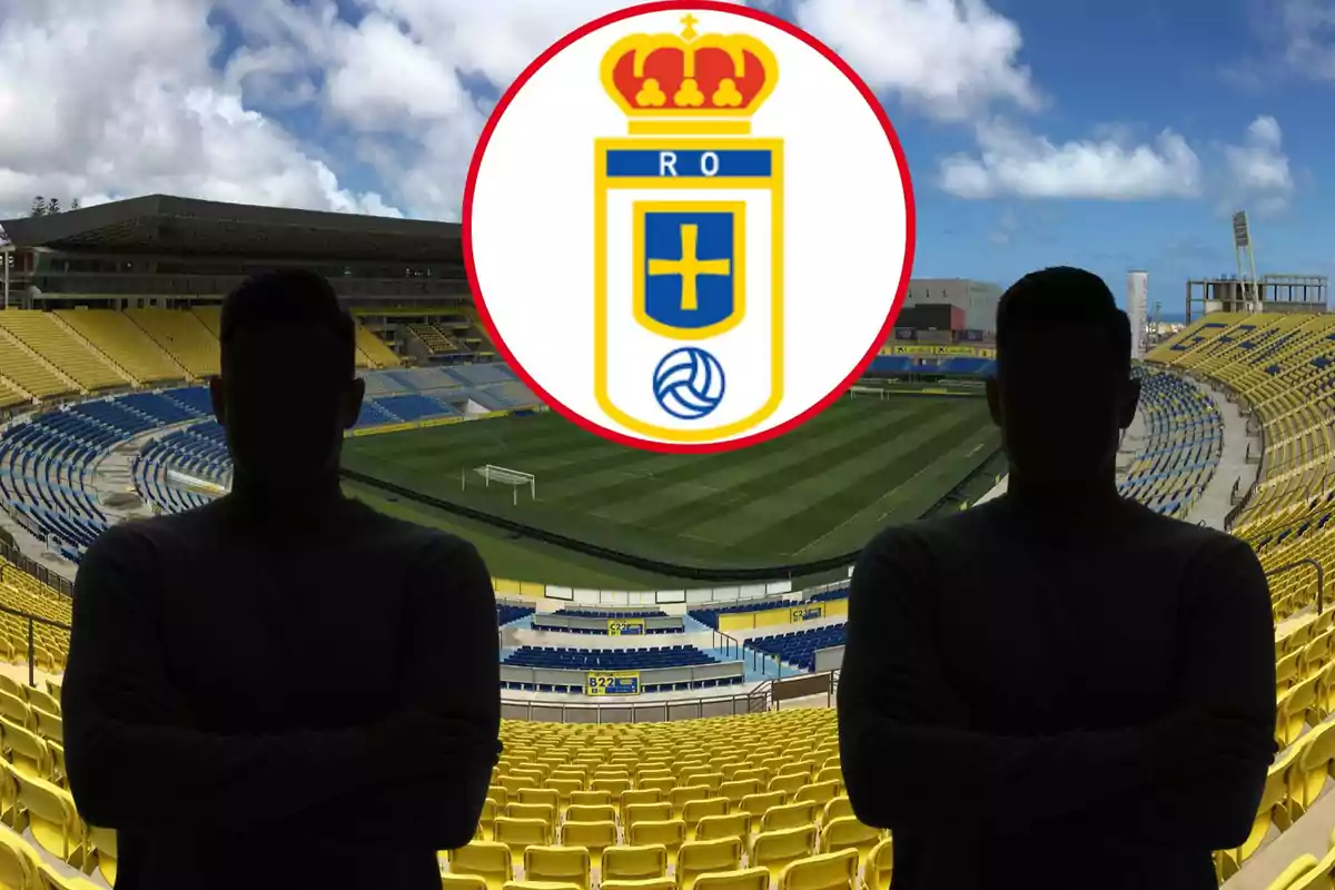 Dues persones amb siluetes fosques posen en un estadi de futbol buit amb seients grocs i blaus, mentre que l'escut del Real Oviedo se superposa a la part superior de la imatge.
