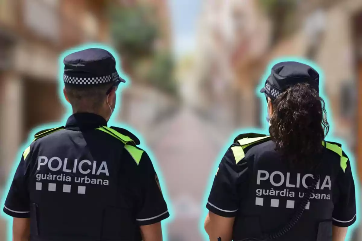 Dos agentes de la policía urbana de espaldas, con uniformes oscuros y detalles reflectantes, patrullando una calle desenfocada.