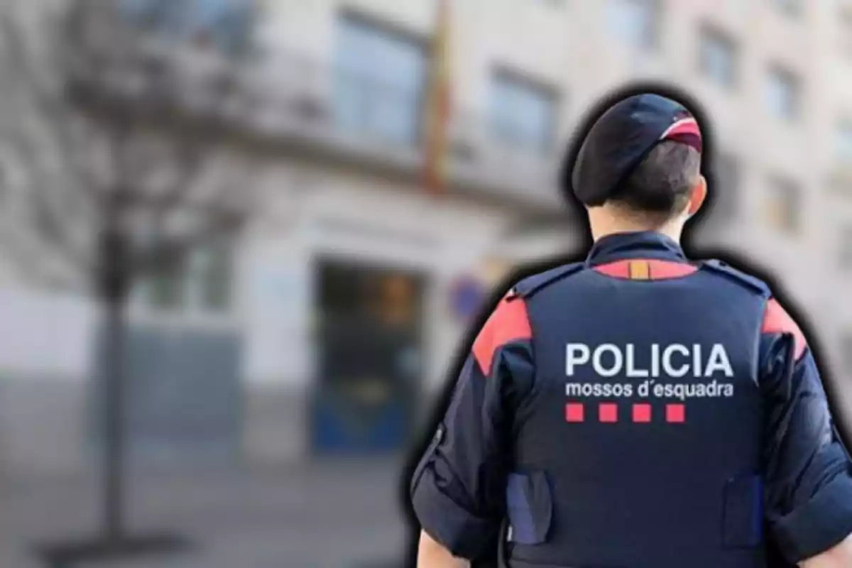 Un agent de policia dels Mossos d?Esquadra d?esquena amb un edifici desenfocat al fons.