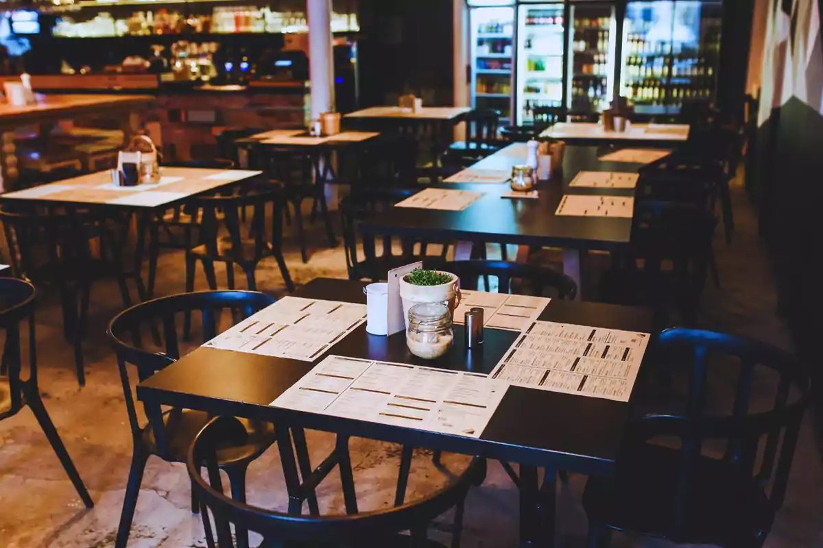 Un restaurant acollidor amb taules preparades i menús disposats en un ambient càlid i modern.