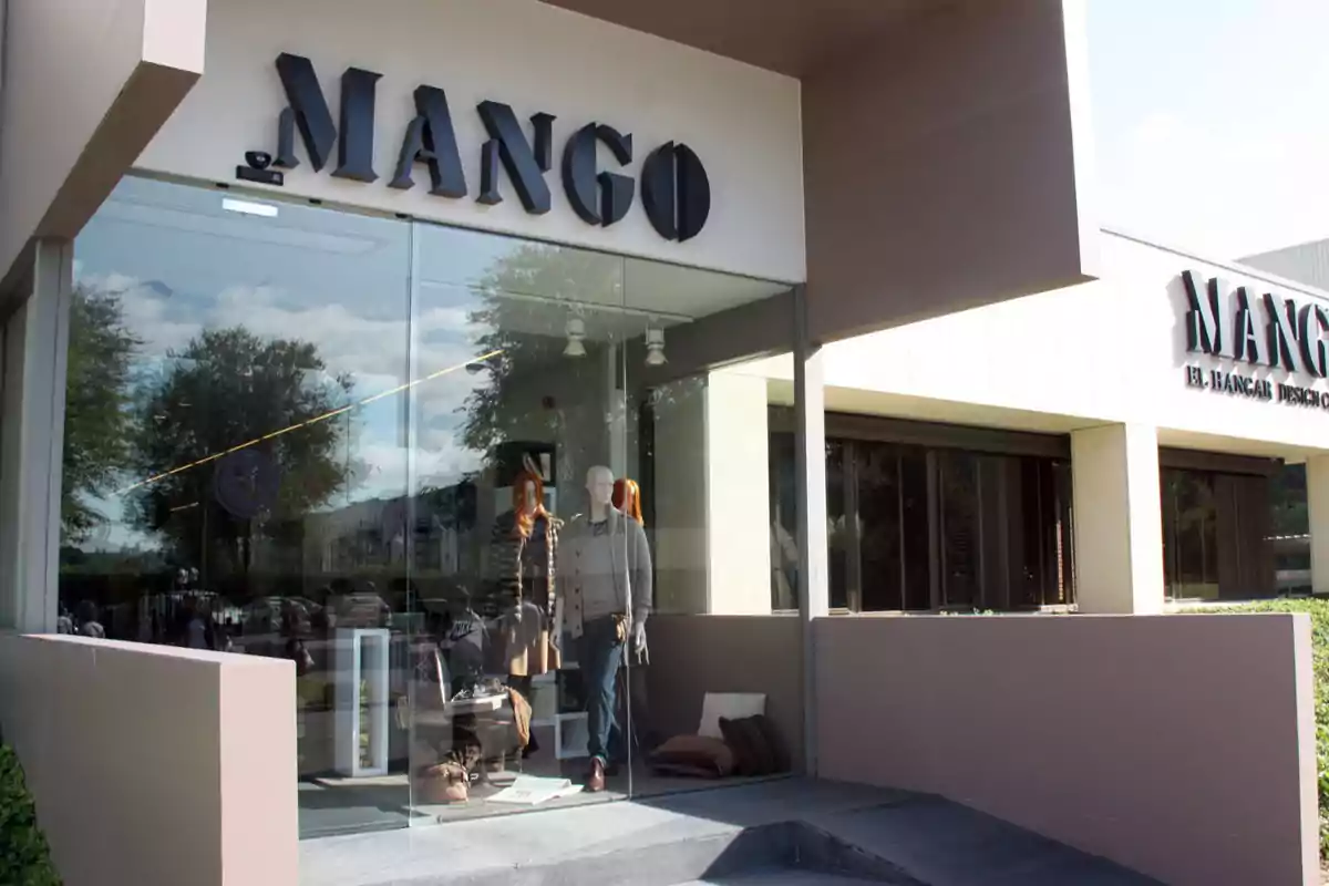 Façana d'una botiga de roba amb maniquins a l'aparador i el logotip de Mango a la part superior.