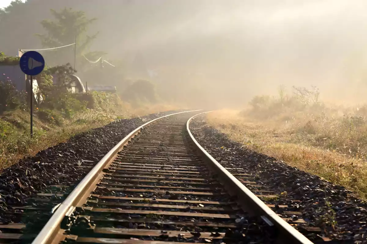 Via de tren corbada en un paisatge rural amb boirina