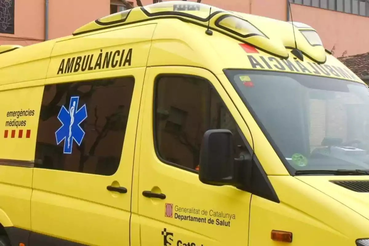 Una ambulància groga amb la inscripció "AMBULÀNCIA" al costat i el logotip d'emergències mèdiques, pertanyent al Departament de Salut de la Generalitat de Catalunya.