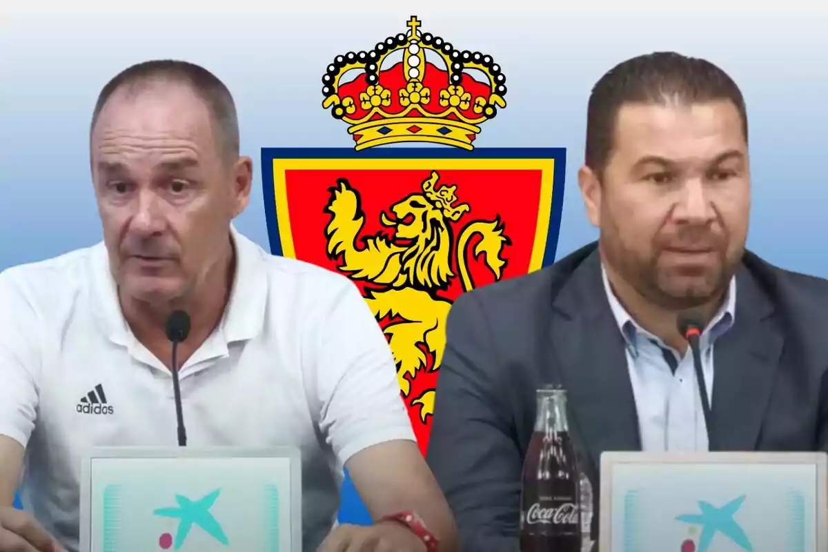 Dos homes en una conferència de premsa amb l'escut d'un lleó coronat darrere seu.