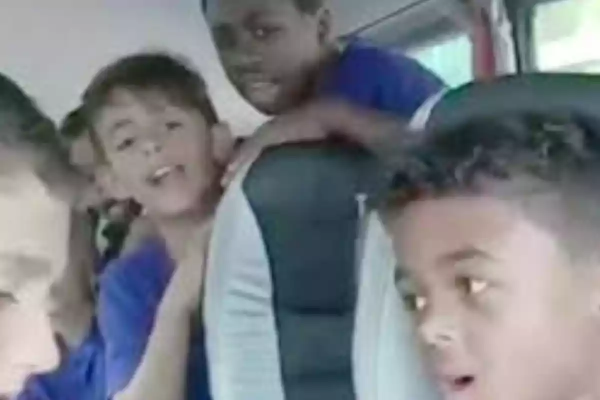 Un grup de nens en un autobús, alguns semblen estar cantant o parlant animadament.